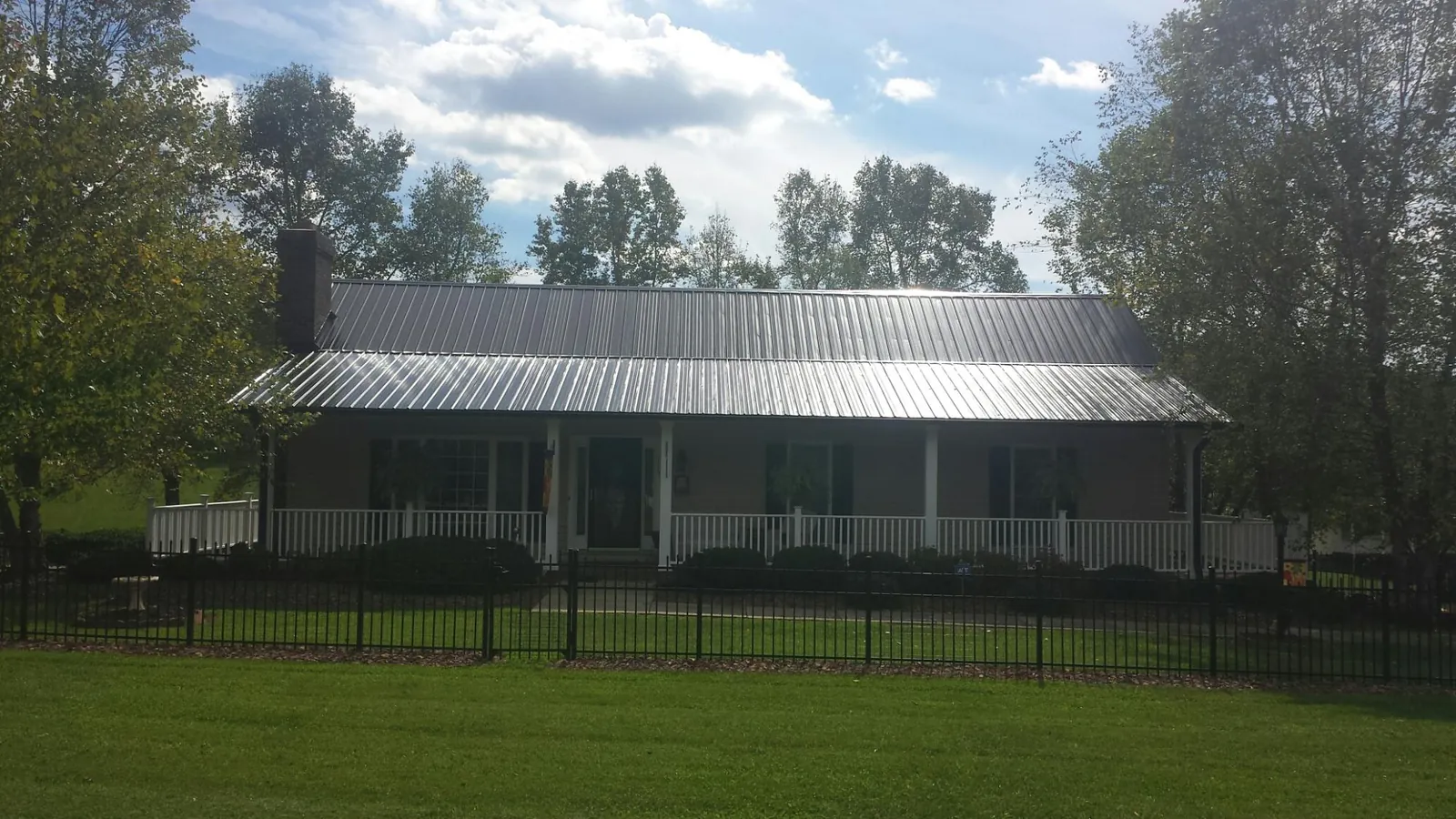 Gray metal roof on a brick ranch with a full width front porch — Gutter Guard Installation work by our crew in Riesel