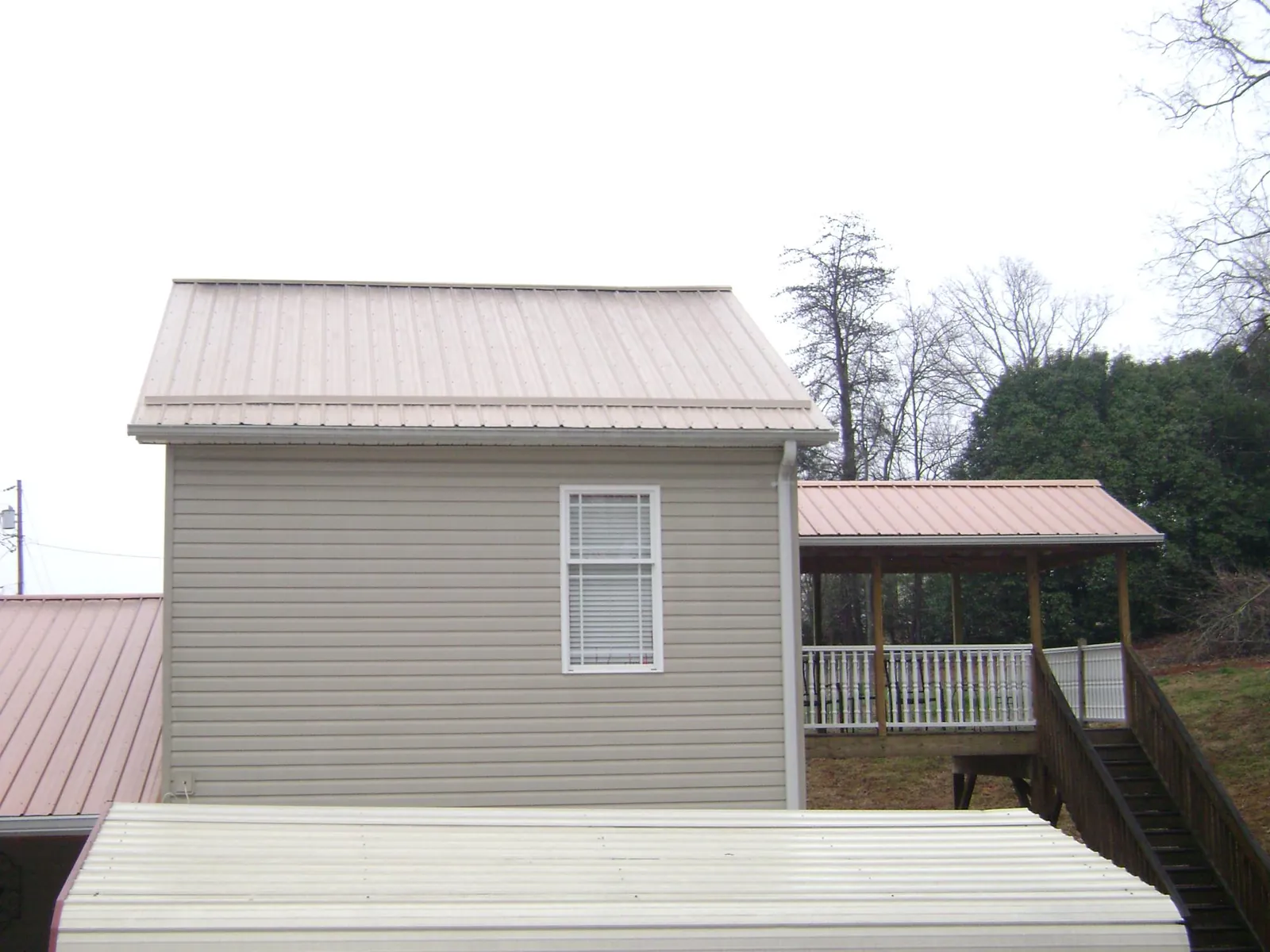 Tan metal roofs on a two story addition and attached porch, from a Roof Replacement job in Riesel